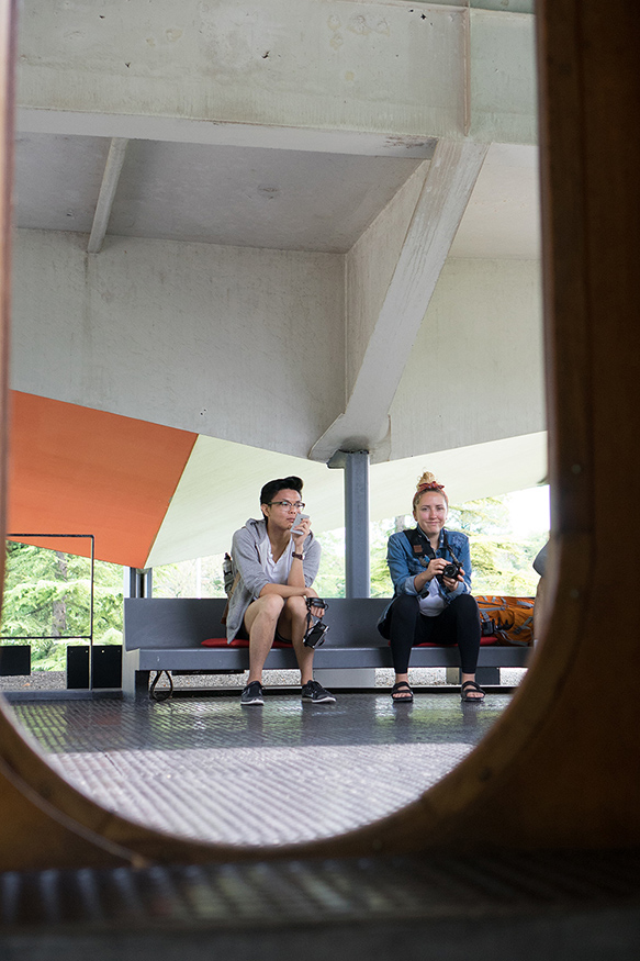 A photo taken through a u shaped portal of two student sititng on a modern design bench