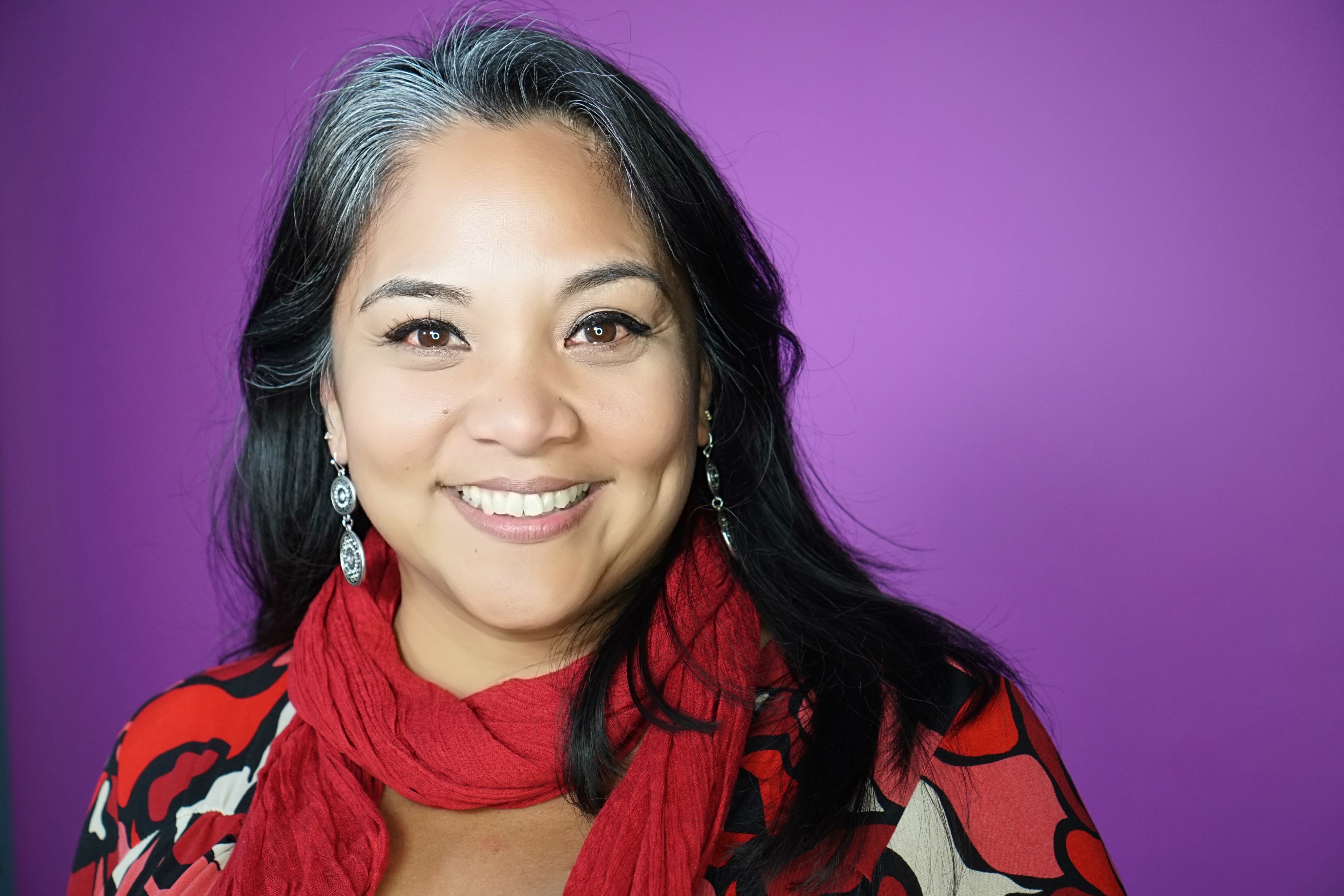Dr. Gerry Ebalaroza-Tunnell in a bright red scarf against a vibrant purple background
