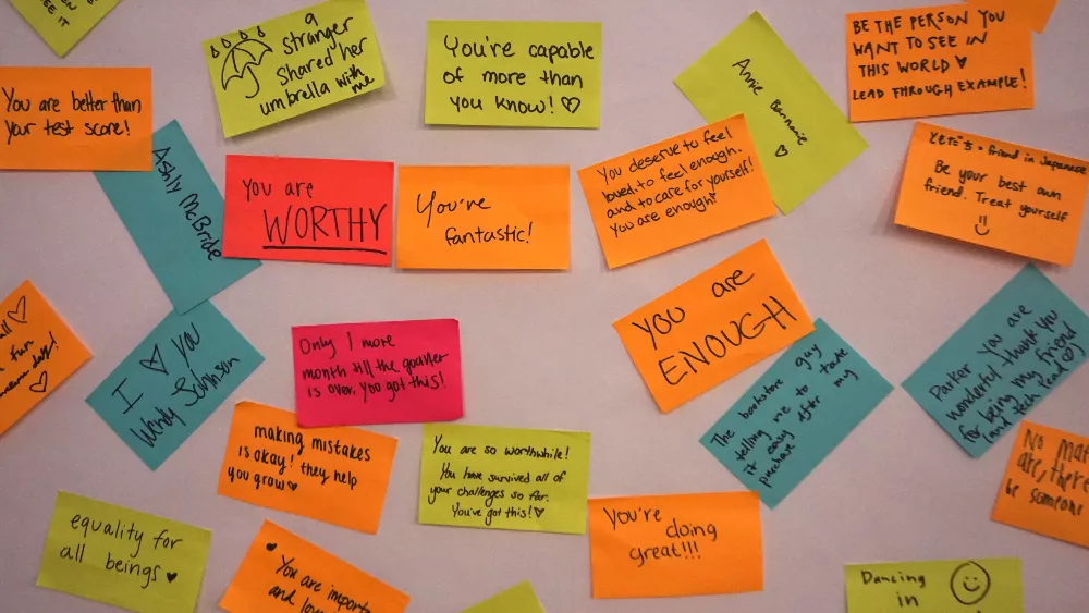 Post-it notes stuck on a wall with words of affirmation written all over them